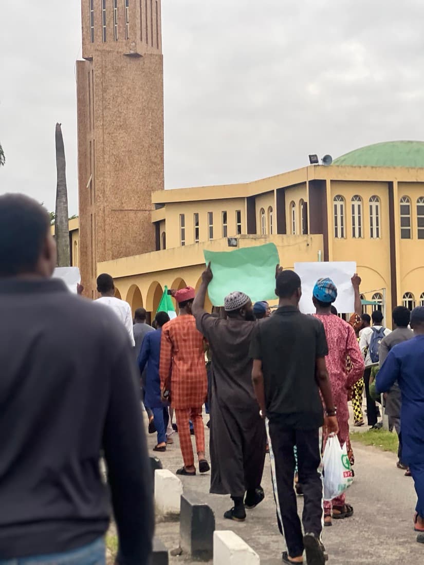 Members walking toward the UNILAG central mosque, one holding up a placard
